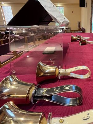Hand bells laying on a burgundy table covering with a stand for sheet music inside the sanctuary of Living Saviour Lutheran Church in Charlotte, North Carolina.